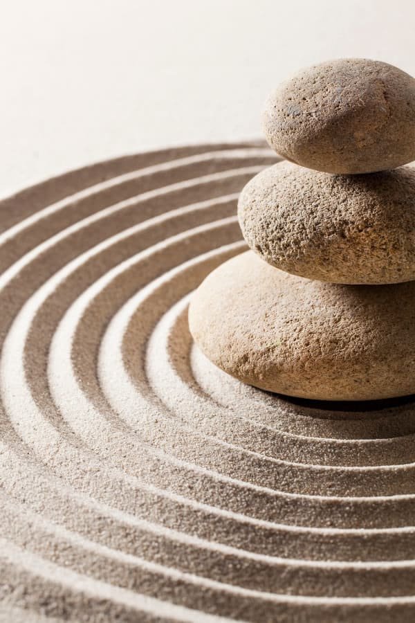 Stacked zen stones on a sand surface symbolize balance, peace, and tranquility, ideal for a wellness or meditation space